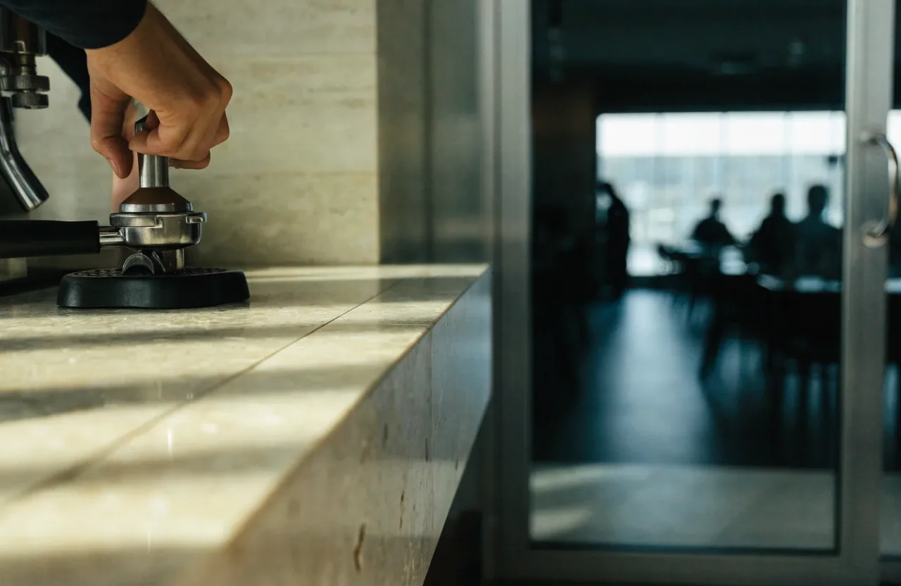 Barista u kamenného pultu při přípravě espressa v lounge kavárně
